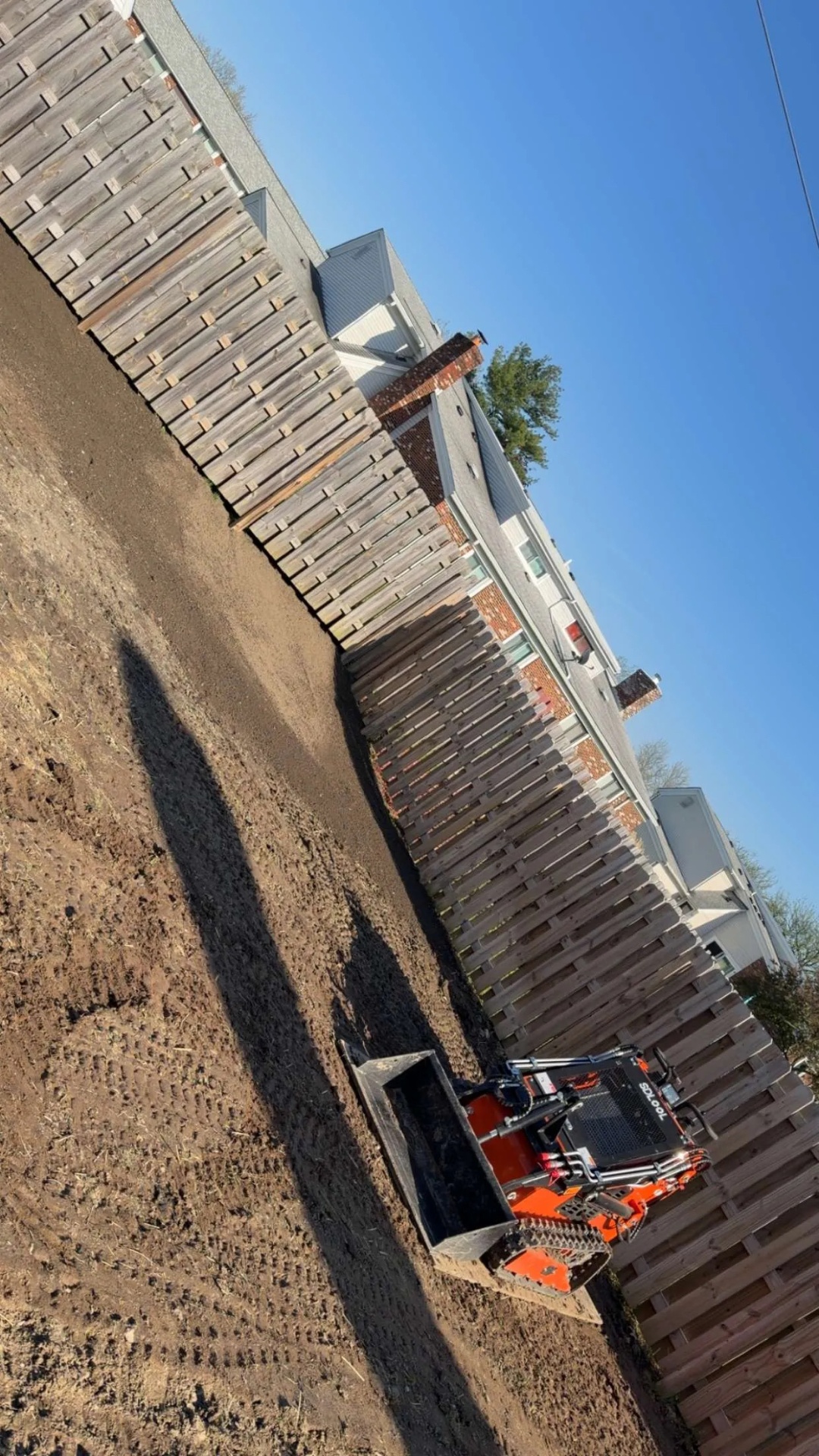 Compact skid steer grading and prepping a yard for new sod