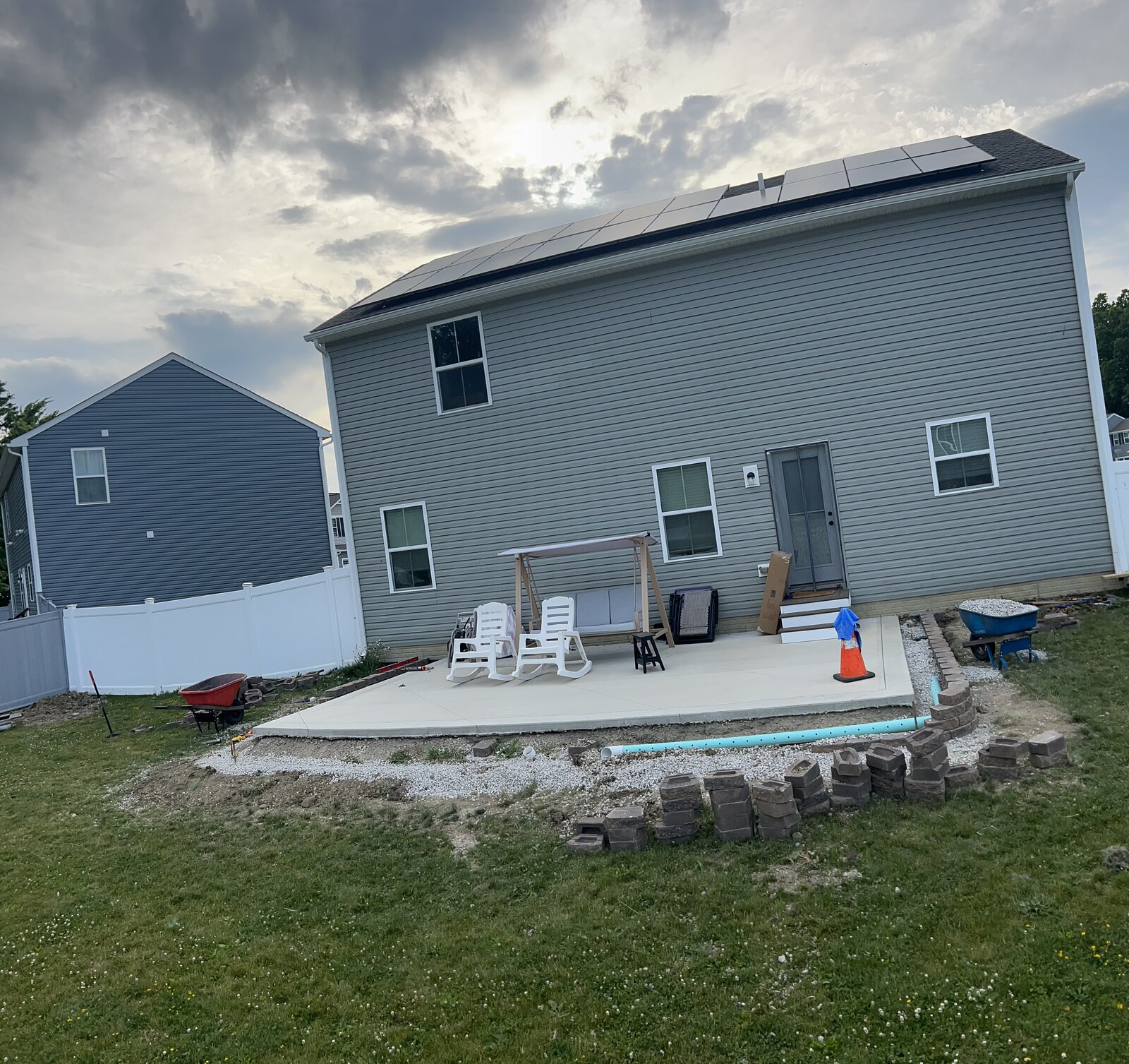New concrete patio with French drain and paver border being built behind a home